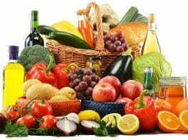 Die biologische Wertigkeit von Eiweiß - Obst, Gemüse, Brot, Eier, Honig, Öl und Wein in und vor einem Einkaufskorb.