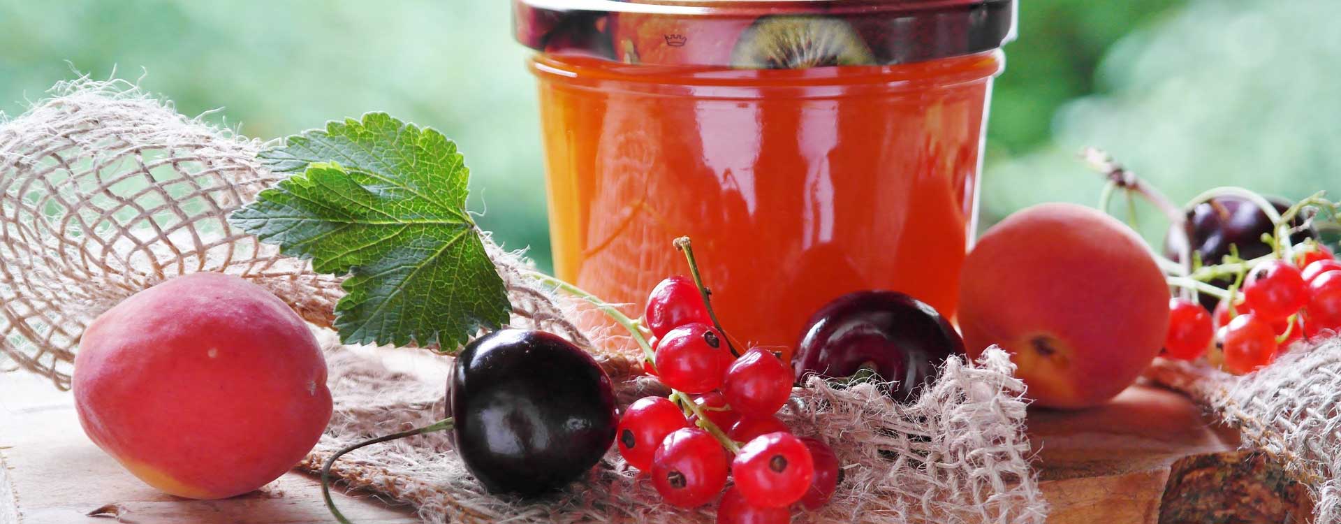 10 Tipps zum Kochen von Marmelade, Konfitüre und Gelee. Konfitüre im Glas und Früchte davor.