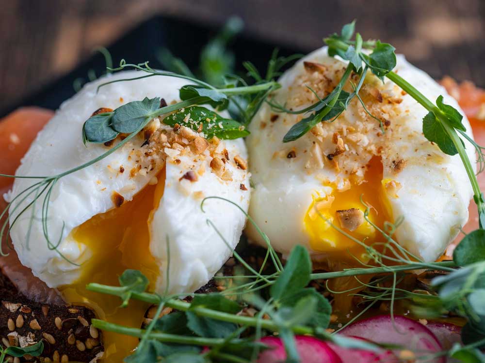 Pochierte Eier auf Vollkornbrot mit Lachs und Microgreens