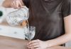 Trinken ist wichtig – Frau schenkt Wasser aus einer Karaffe in ein Glas
